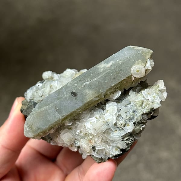 Grey double-terminated quartz on coin-shaped calcite from Inner Mongolia, China, close-up of the crystal faces