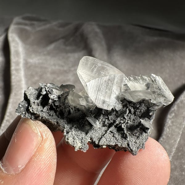 Clear serrated baryte blade on dark calcite from Guangxi, China, detail of the matrix contact