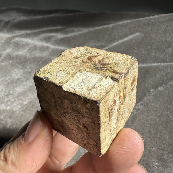 Large golden-brown limonite cube pseudomorph after pyrite from Guangxi, China, detail of the matrix contact