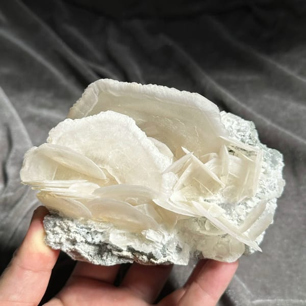 Large translucent platy calcite crystals stacked like petals from Hunan, China, held in hand