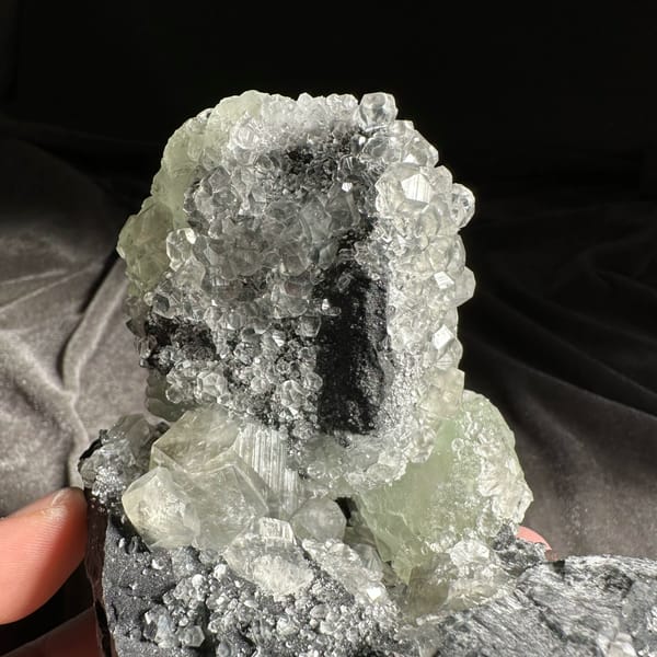Mountain-shaped pale green fluorite cluster on dark quartz from Fujian, China, close-up of the crystal faces