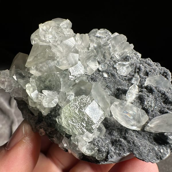 Clear star-patterned calcite with green fluorite on dark druse from Fujian, China, close-up of the crystal faces