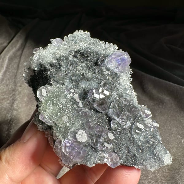 Stepped purple and green fluorite cubes on grey quartz druse from Fujian, China, close-up of the crystal faces