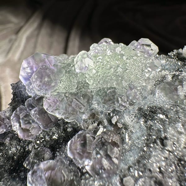 Stepped purple and green fluorite cubes on grey quartz druse from Fujian, China, reverse side
