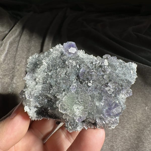 Stepped purple and green fluorite cubes on grey quartz druse from Fujian, China, detail of the matrix contact