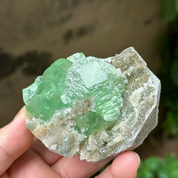 Cross-shaped stack of transparent green fluorite cubes from Fujian, China, held in hand