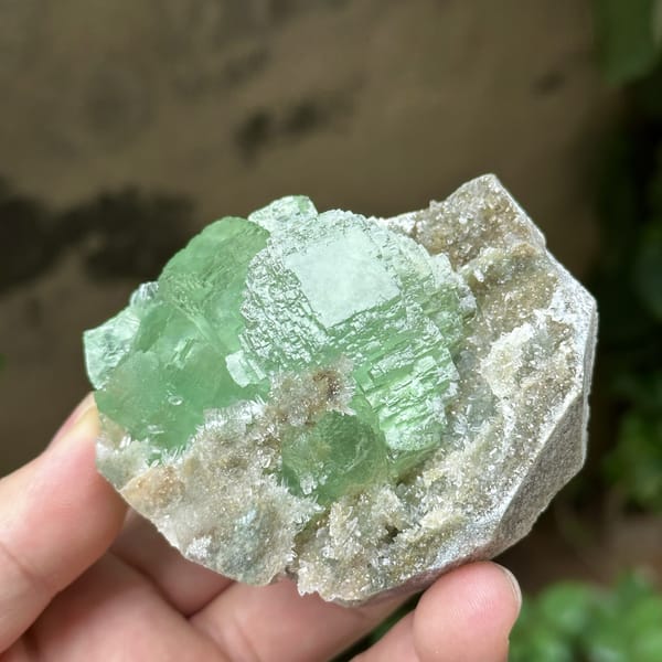 Cross-shaped stack of transparent green fluorite cubes from Fujian, China, detail of the matrix contact