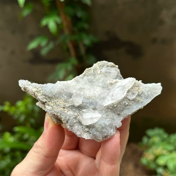 Double-terminated calcite on pale fluorite and quartz from Hunan, China, held in hand