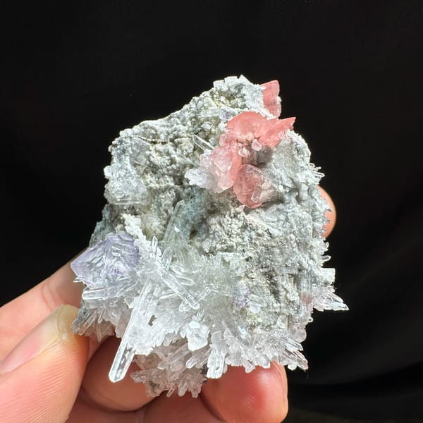 Pink rhodochrosite and purple fluorite with quartz needles from Wuzhou, Guangxi, China, close-up of the crystal faces