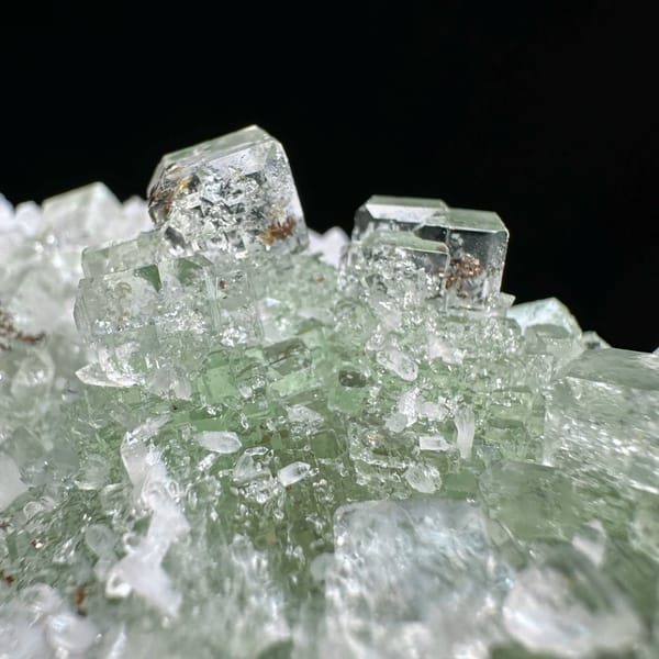 Stepped glassy green fluorite with inclusions on white quartz from Guangdong, China, close-up of the crystal faces