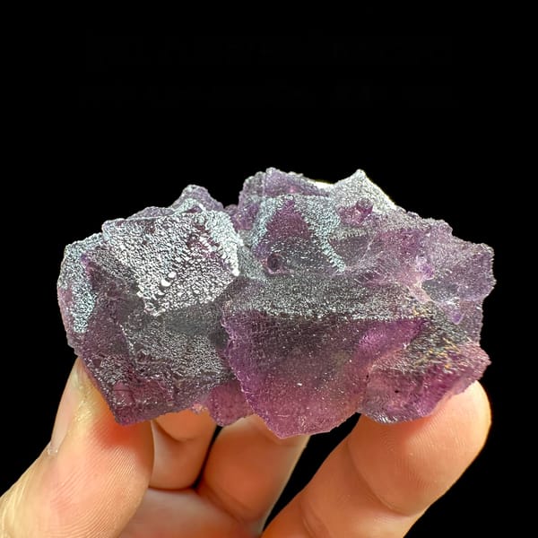 Purple and green stepped octahedral fluorite from Zhejiang, China, held in hand