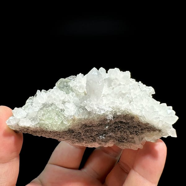 White quartz druse plate with pale green fluorite from Guangdong, China, held in hand