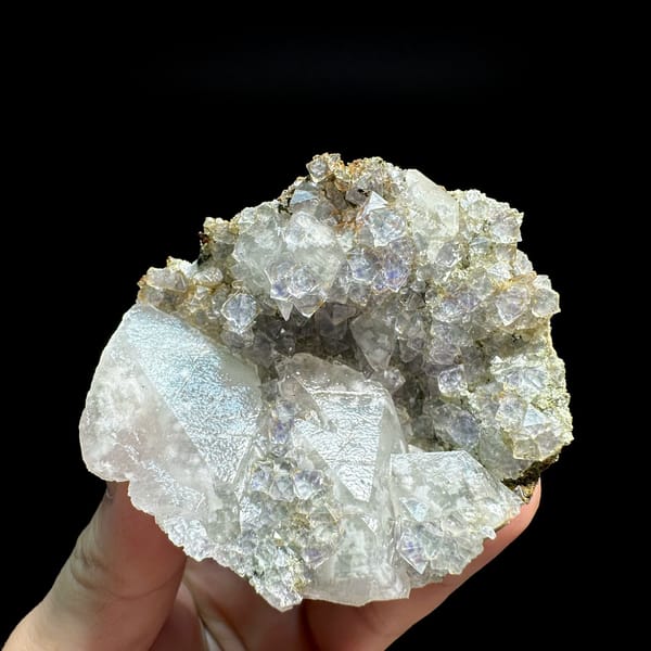 Pale blue-cored fluorite octahedra with white calcite from Fujian, China, held in hand