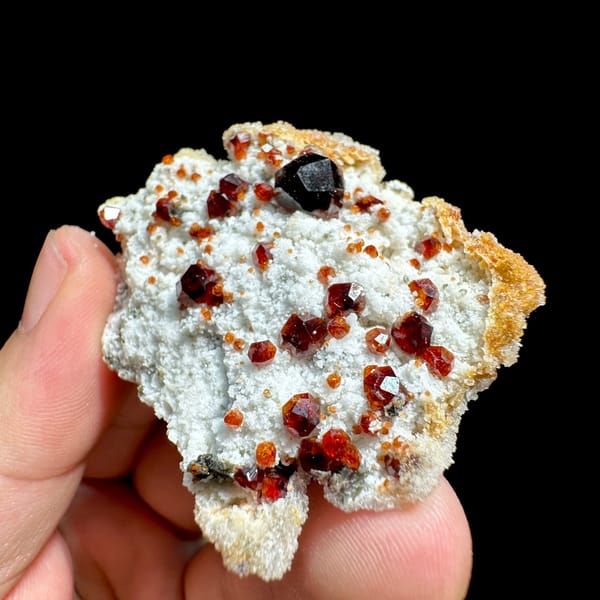 Large dark-red garnets with hyalite opal on white feldspar from Yunxiao, Fujian, China, close-up of the crystal faces