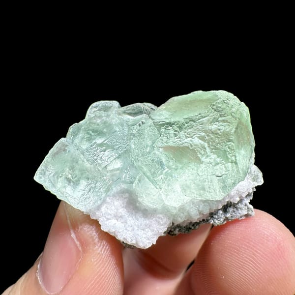 Two glassy mint-green fluorite cubes on quartz from Xianghualing, Hunan, China, close-up of the crystal faces