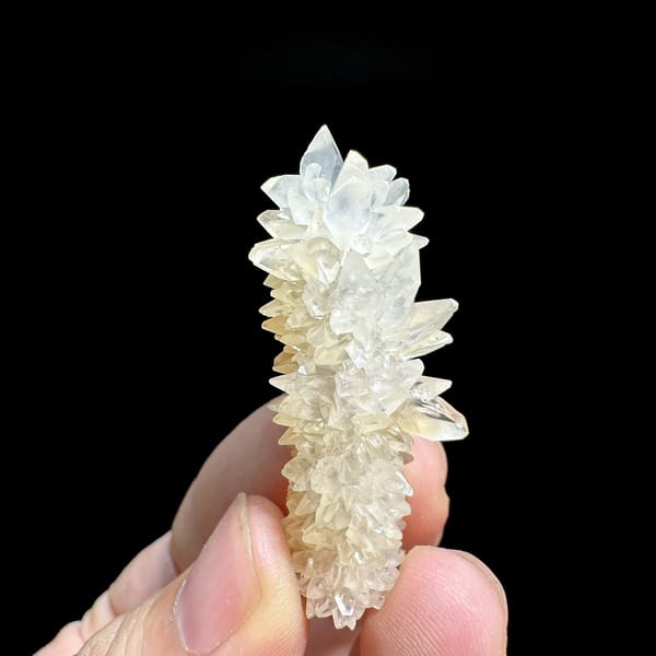Slender pillar of stacked white calcite crystals from Yunnan, China, detail of the matrix contact