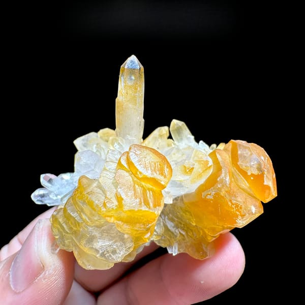 Orange-skinned calcite blades with clear quartz spire from Fujian, China, held in hand