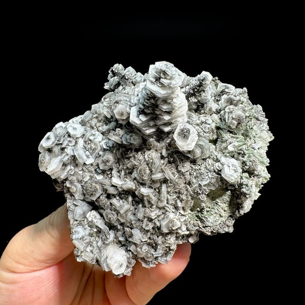 Hexagonal tower calcite crystals on grey quartz from Fujian, China, held in hand