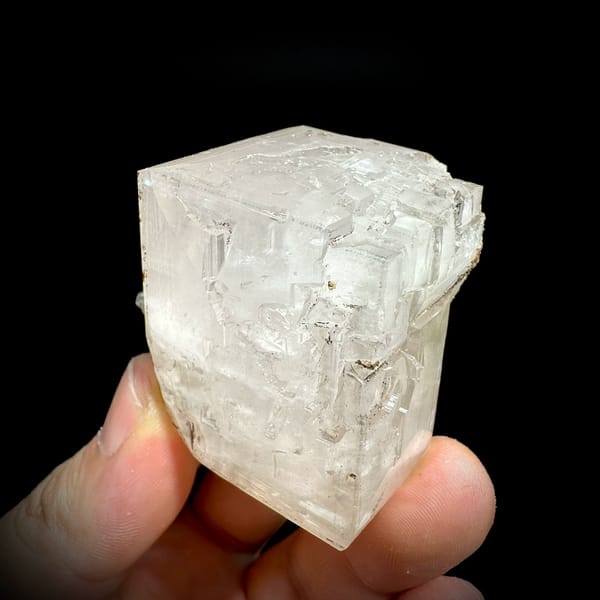 Large colourless calcite rhomb with pyrite from Fujian, China, held in hand