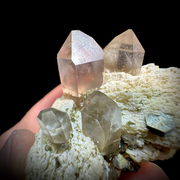 Pale smoky quartz points on cream feldspar with mica from Yunxiao, Fujian, China, close-up of the crystal faces