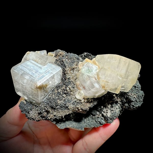 Star calcite crystals enclosing green fluorite on dark matrix from Fujian, China, held in hand