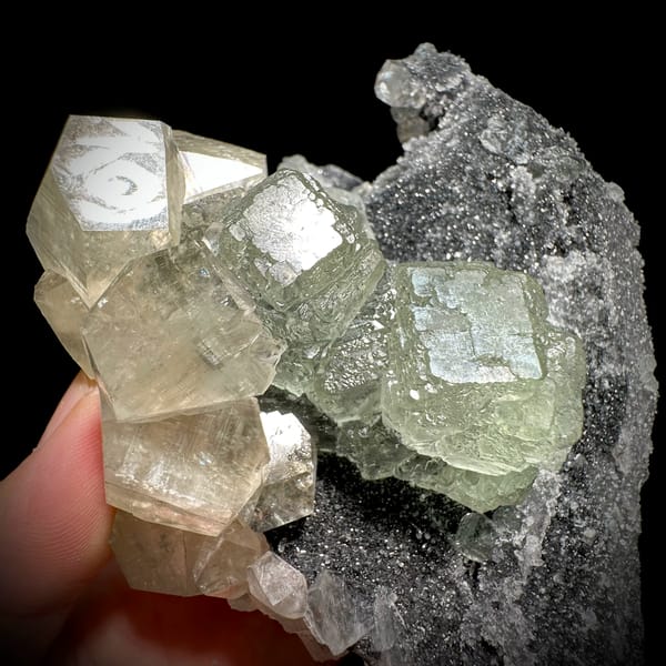 Pale green fluorite cubes with calcite on dark quartz from Fujian, China, close-up of the crystal faces