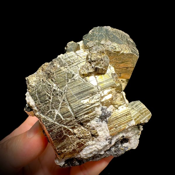 Heavy brass-gold pyrite block with striated faces and galena from Hunan, China, close-up of the crystal faces