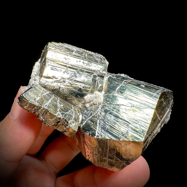 Two interlocking striated brass-gold pyrite crystals from Hunan, China, close-up of the crystal faces