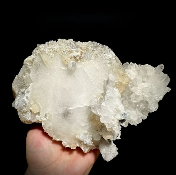 Huge tabular calcite plate over sparkling quartz from Fujian, China, held in hand