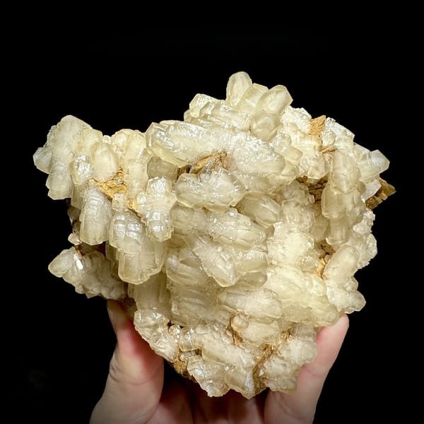 Mound of hammer-headed cream calcite crystals from Guizhou, China, detail of the matrix contact