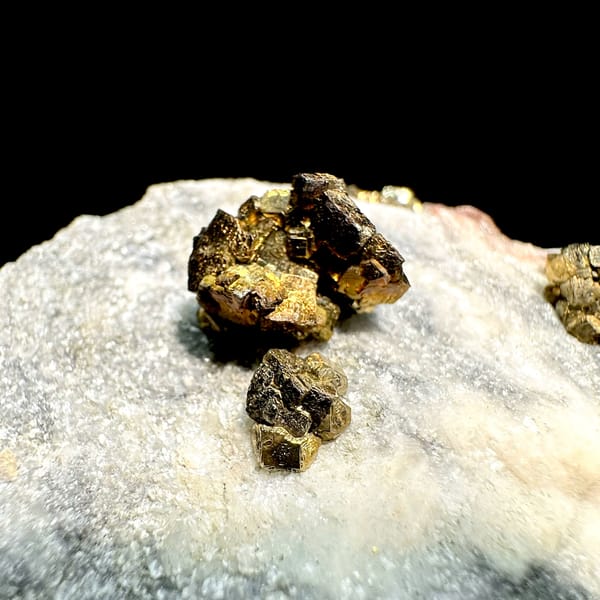 Brassy pyrite crystal clusters on pale sugary plate from Fujian, China, close-up of the crystal faces