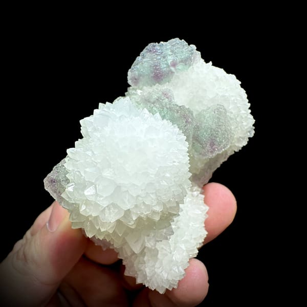 Purple-green fluorite balls beside white quartz needles from Fujian, China, close-up of the crystal faces