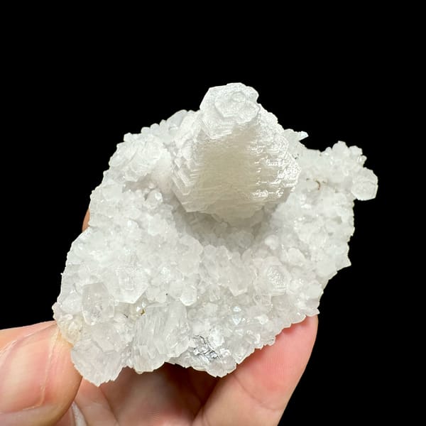 White pagoda calcite tower on quartz druse from Guangdong, China, close-up of the crystal faces