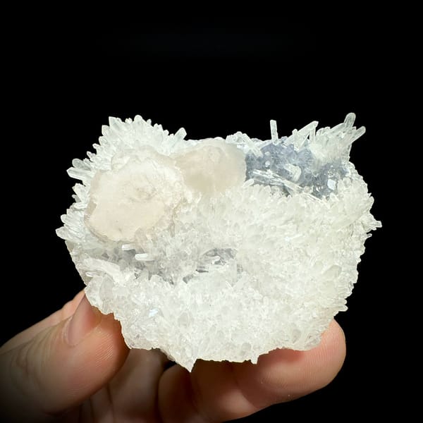 White quartz needles with calcite discs and pale blue fluorite from Fujian, China, held in hand
