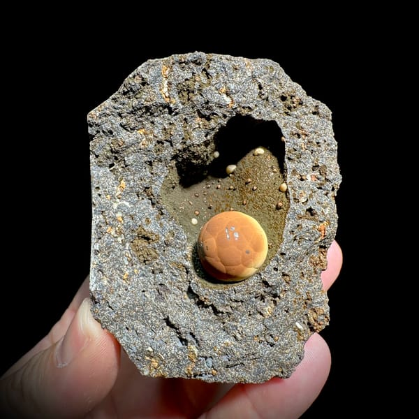 Football-shaped orange calcite ball in grey rock pocket from Fujian, China, second angle
