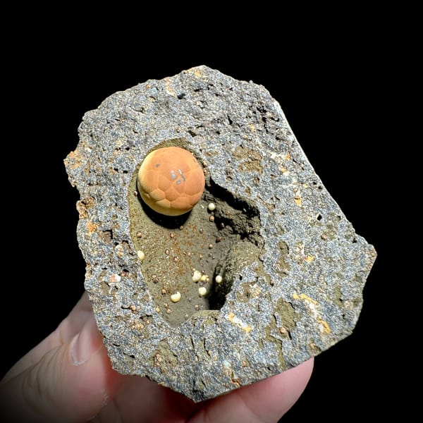 Football-shaped orange calcite ball in grey rock pocket from Fujian, China, reverse side