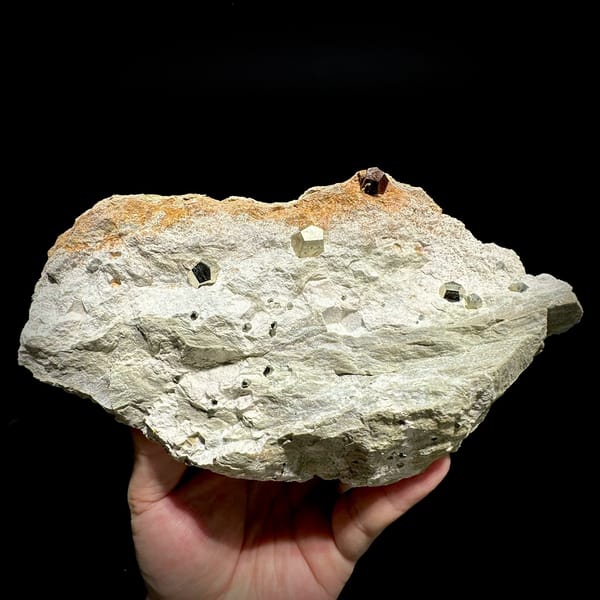 Small pyritohedral pyrite crystals on pale matrix block from Guangxi, China, held in hand