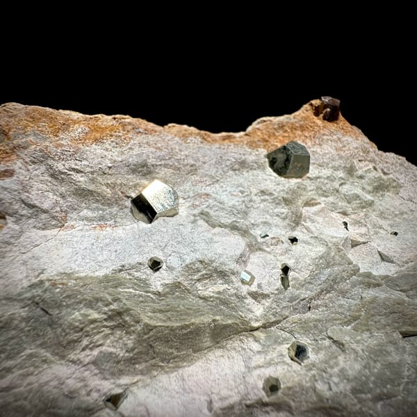 Small pyritohedral pyrite crystals on pale matrix block from Guangxi, China, close-up of the crystal faces