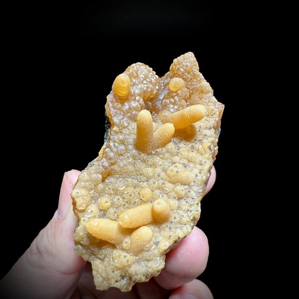 Orange caterpillar-form calcite over cream botryoidal plate from Yunxiao, Fujian, China, detail of the matrix contact