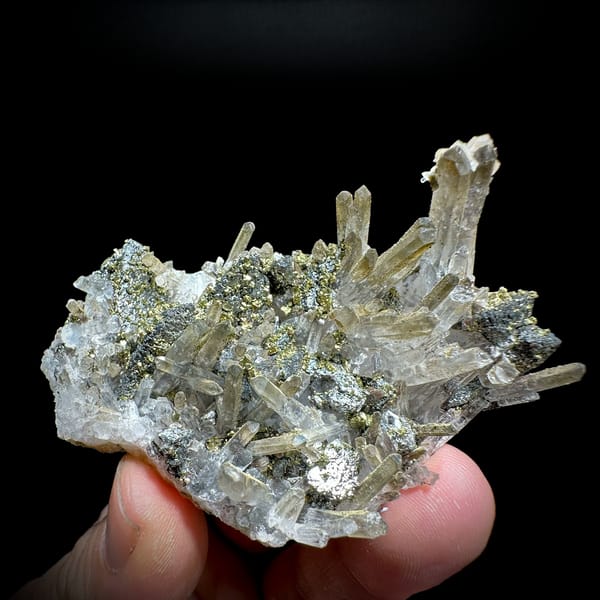 Clear quartz needles with chalcopyrite and freibergite from Inner Mongolia, China, held in hand