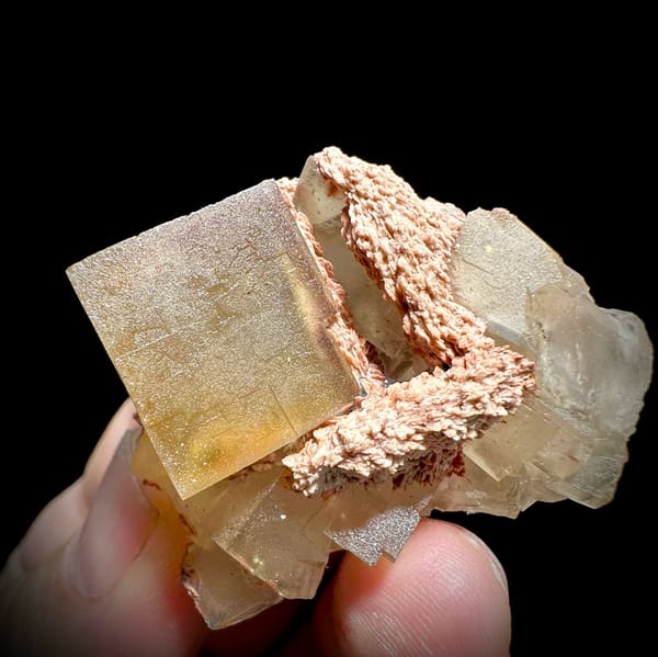 Honey-yellow fluorite cube on pink baryte and calcite from Beijing, China, close-up of the crystal faces