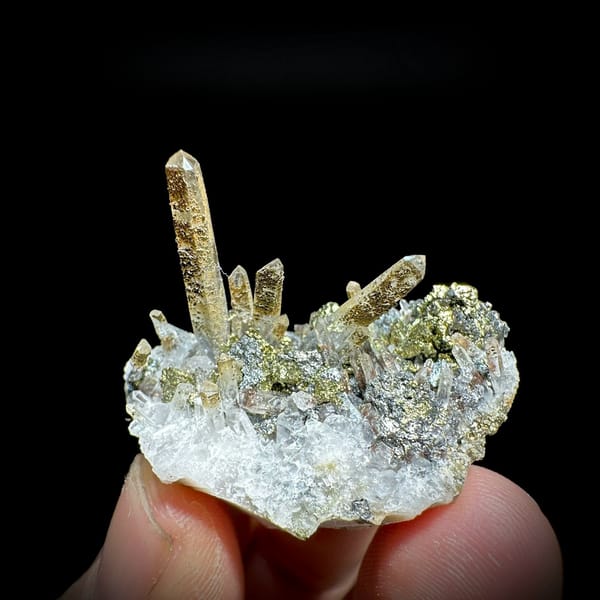 Clear quartz points with chalcopyrite and freibergite from Inner Mongolia, China, held in hand
