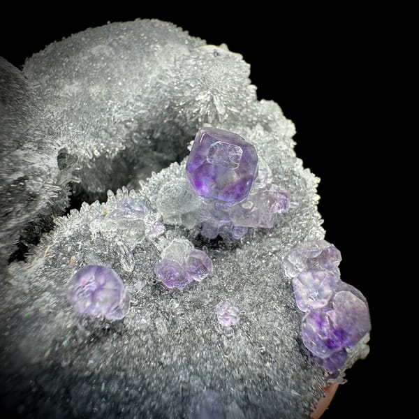 Purple fluorite octahedra on grey quartz mound from Fujian, China, close-up of the crystal faces