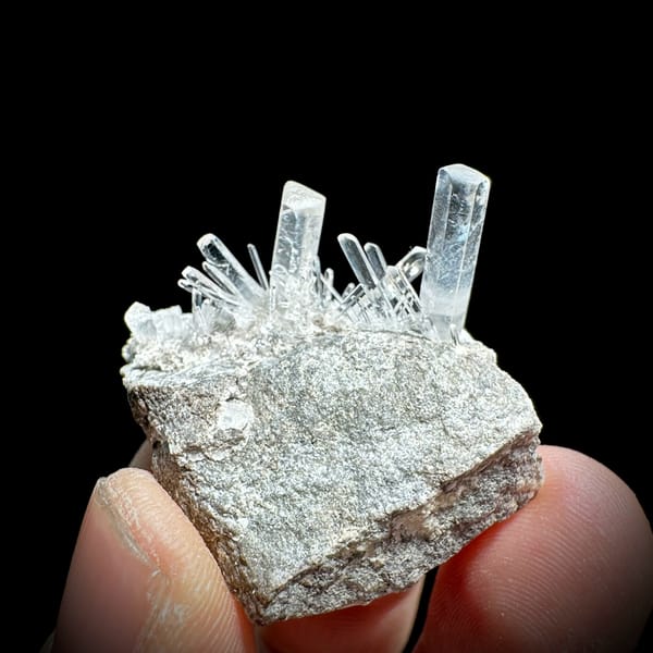 Long transparent aurora calcite prisms on grey rock from Zhejiang, China, close-up of the crystal faces