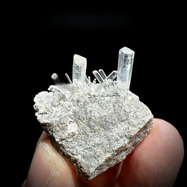 Long transparent aurora calcite prisms on grey rock from Zhejiang, China, detail of the matrix contact