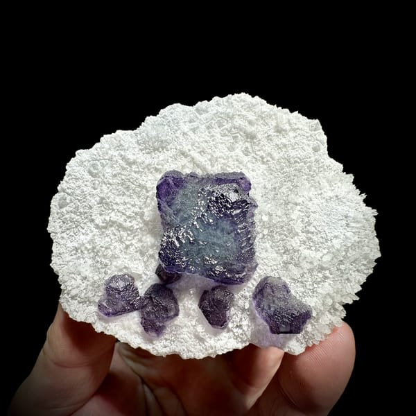 Large purple fluorite cube with small cubes on white quartz plate from Zhejiang, China, close-up of the crystal faces
