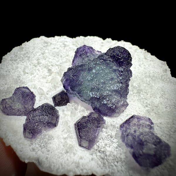 Large purple fluorite cube with small cubes on white quartz plate from Zhejiang, China, top view