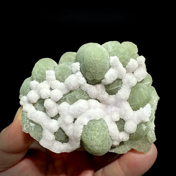 Mint-green fluorite balls laced with white fluorite from Henan, China, held in hand