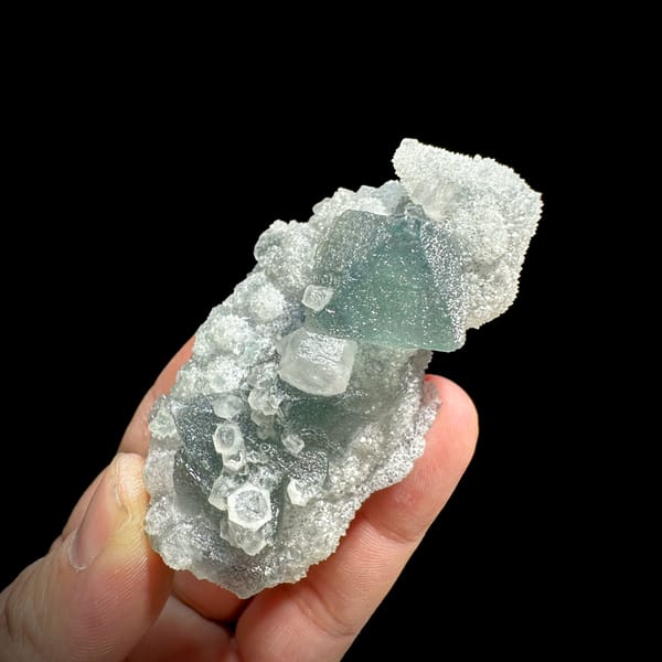 Green fluorite octahedron and hexagonal calcite on white quartz from Fujian, China, close-up of the crystal faces