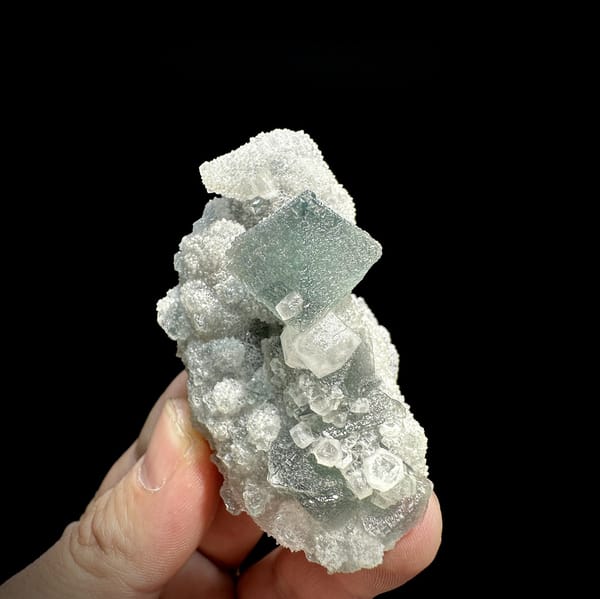 Green fluorite octahedron and hexagonal calcite on white quartz from Fujian, China, detail of the matrix contact